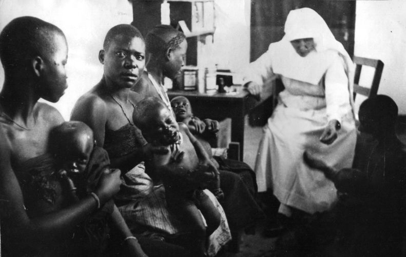 Wachtende moeders met kinderen in een polikliniek van de Witte Zusters