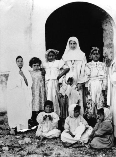Witte Zuster met Tunesische meisjes voor een kerk in Carthago 
